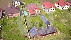 Aerial view of a residential private house with solar panels on roof and wind generator turbine.