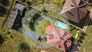 Aerial view of a residential private house with solar panels on roof and wind generator turbine.