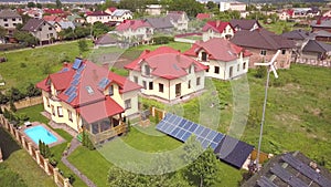Aerial view of a residential private house with solar panels on roof and wind generator turbine.