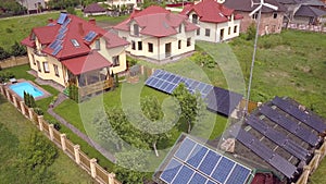 Aerial view of a residential private house with solar panels on roof and wind generator turbine.