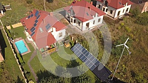 Aerial view of a residential private house with solar panels on roof and wind generator turbine