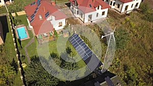 Aerial view of a residential private house with solar panels on roof and wind generator turbine