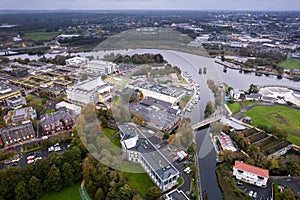 Aerial view on River Corrib in Galway city, Ireland. Dam and remains of old bridge in the foreground. Warm sunset sky with light