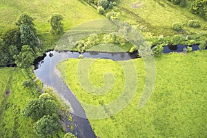 Aerial view of river and empty green meadow field