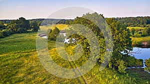 Aerial view of river in green meadows, beautiful sunset light