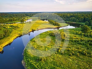 Aerial view of river in green meadows, beautiful sunset light. Meander evening panorama