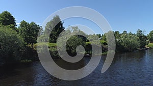 Aerial view of a river in summer village and an old wooden house. Shot. Forest and small house surrounded by green trees