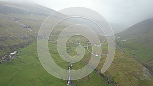 Aerial view of rivers and green hills in Saksun, Faroe Islands on a foggy day