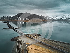 Aerial view of road 1 in iceland with bridge over the sea in Snaefellsnes peninsula with clouds, water and mountain in