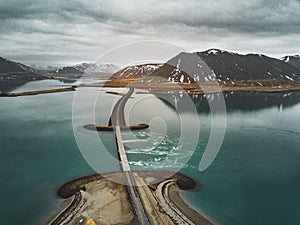 Aerial view of road 1 in iceland with bridge over the sea in Snaefellsnes peninsula with clouds, water and mountain in