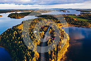 Aerial view of road through autumn forest with blue lakes in Finland