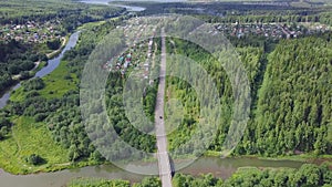 Aerial view of a road in autumn surrounded by pine tree forest. Clip. Top view of the road in the forest