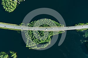 Aerial view of road through blue lakes or sea with green woods in Finland