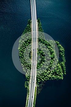 Aerial view of road through blue lakes or sea with green woods in Finland