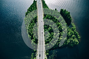 Aerial view of road through blue lakes or sea with green woods in Finland