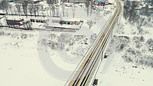 Aerial view of a road bridge across a frozen river in winter drives cars.