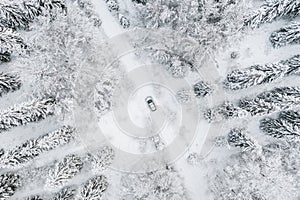 Aerial view of road with car in winter time, car driving in snow forest