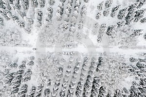 Aerial view of road with car in winter time, car driving in snow forest