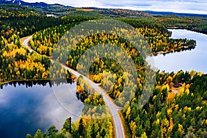 Aerial view of road and colorful autumn  forest with mountains and blue lakes in Finland