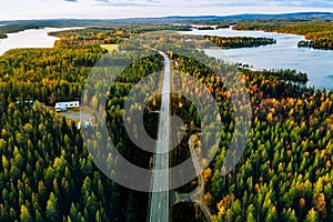 Aerial view of road and forest in autumn colors with blue water lake