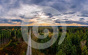 Aerial view of road among the forest and trees. Sunset field in southern germany near the alps.