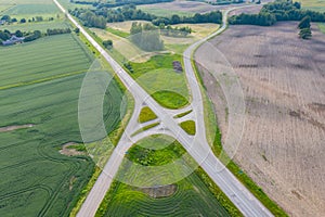 Aerial view of road interchange or intersection with no traffic on the road. Green rural area