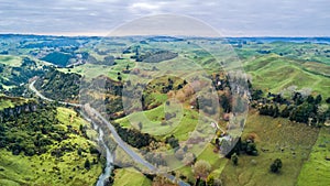 Aerial view on a road running along a river through mountain valley with rocks on the background. Taranaki region, New Zealand