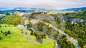 Aerial view on a road running along a river through mountain valley with rocks on the background. Taranaki region, New Zealand