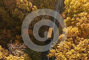 Aerial view of road with school bus in beautiful autumn forest