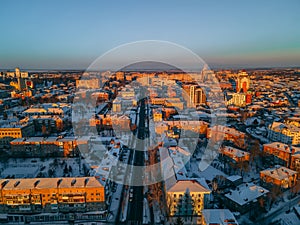 Aerial view of road in small european city with snow covered roofs at winter sunset