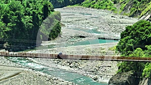 Aerial view of road and small  hanging bridge over  mountain river