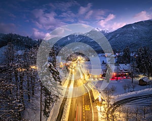 Aerial view of road, snowy mountains, street lights at night