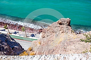 Aerial view of rock formation on arid terrain, road, boardwalk and rocky coastal beach