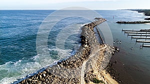 Aerial view of rock sea wall boat harbour with stand up paddle boarders near piers