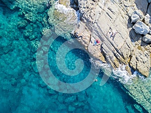 Aerial view of rocks on the sea. Swimmers, bathers floating on the water. eople sunbathing on the towel photo