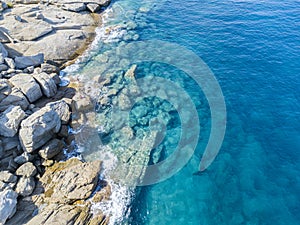 Aerial view of rocks on the sea. Swimmers, bathers floating on the water. People sunbathing on the towel