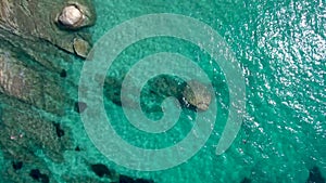 Aerial view of rocky beach with turquoise water in Halkidiki Kavourotripes, Greece, upward movement by drone