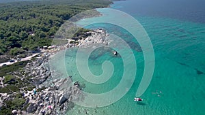 Aerial view of rocky beach with turquoise water in Halkidiki Kavourotripes, Greece, upward movement by drone, 4K resolution