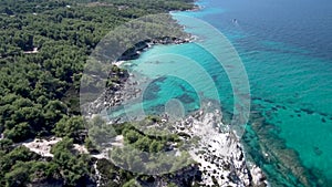 Aerial view of rocky beach with turquoise water in Halkidiki Kavourotripes, Greece, upward movement by drone, 4K resolution