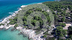 Aerial view of rocky beach with turquoise water in Halkidiki Kavourotripes, Greece, upward movement by drone, 4K resolution