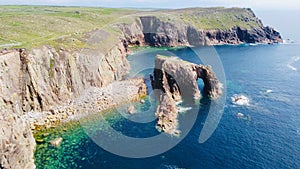 Aerial view of a rocky coastline with the Enys Dodnan Arch