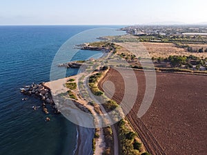 Aerial view of a rocky coastline near a plowed soil field at Jardi de Sol de Riu, Vinaros, Spain