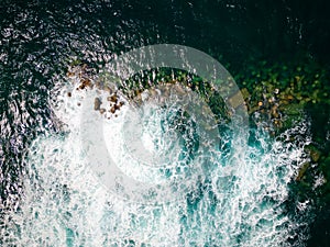 Aerial view of a rough sea crashing against rocks next to a lighthouse (Chania, Crete, Greece