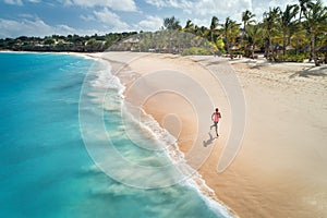 Aerial view of the running young woman on the sandy beach