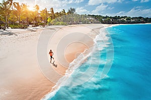 Aerial view of the running young woman on the sandy beach