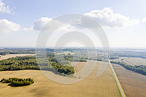 Aerial view of rural area with fields and green forests in sunny summer day