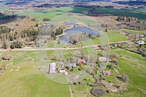 Aerial view of rural area with houses and lake surrounded with forest and fields