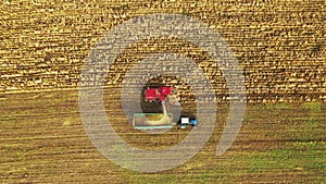 Aerial View Of Rural Landscape. Combine Harvester And Tractor Working In Corn Field. Collects Dry Corn Plants