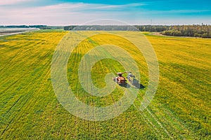 Aerial View Of Rural Landscape. Combine Harvester And Tractor Working Together In Field. Harvesting Of Oilseed In Spring