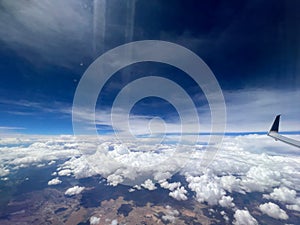 Aerial view of a rural landscape enveloped in puffy clouds in blue sky background